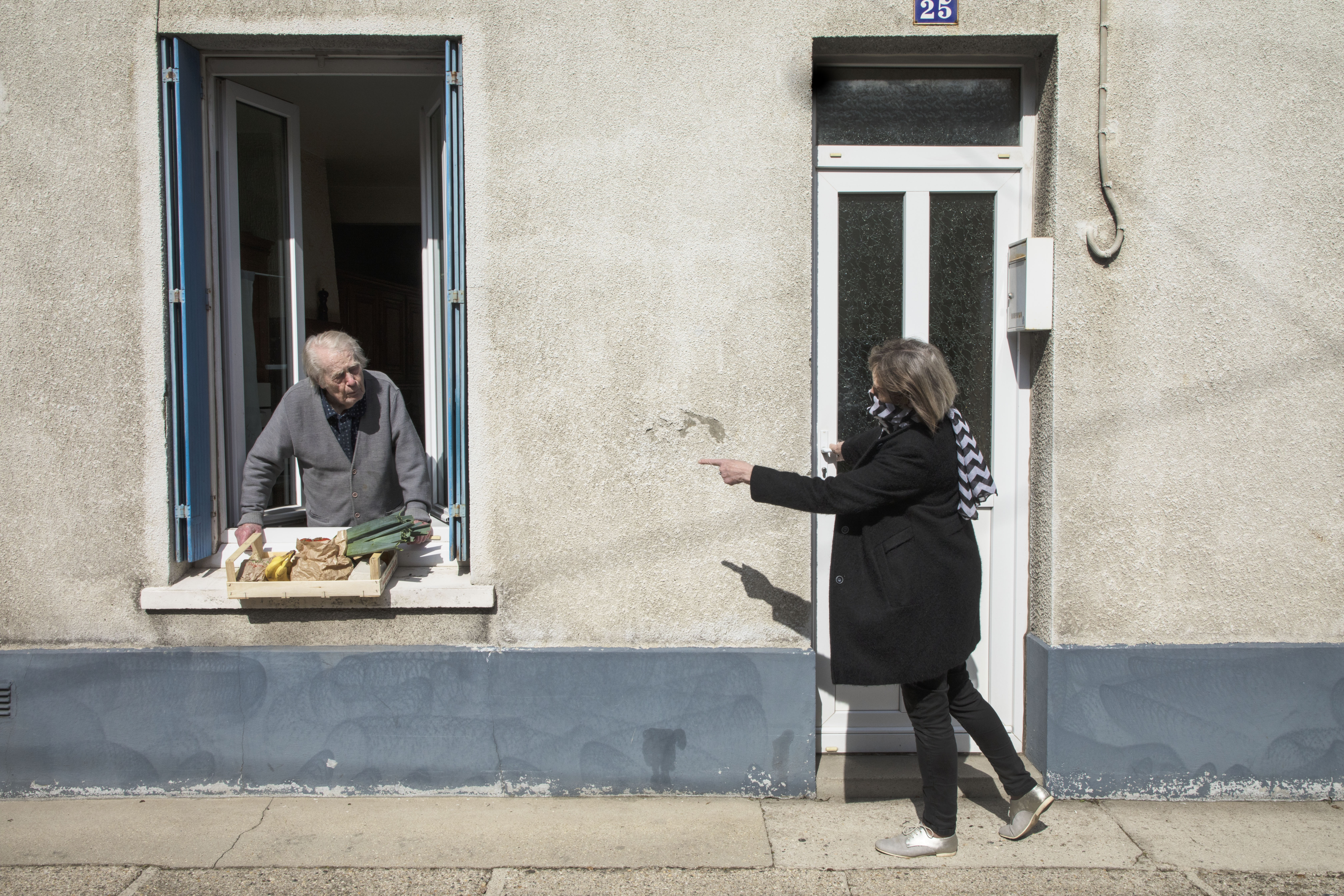 The Graduate Institute and the CEPR co-organize an online public talk by Professor Pierre Yared on his paper "Pandemic Lockdown: The Role of Government Commitment". His work focuses on the importance of credible rules that allow governments to curb a pandemic while limiting the economic costs of a lockdown. This picture shows someone bringing food to an elderly man as part of a neighbourhood solidarity action during the coronavirus lockdown in Fécamp, Normandy, France. Taken by Magnum partner Jean Gaumy.