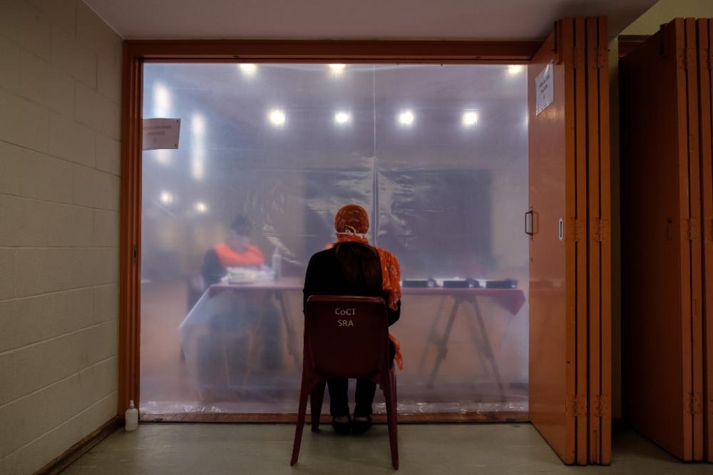 A patient in consultation with healthcare workers before being tested for Coronavirus COVID-19 at the Schotsche Kloof Civic Centre in the historical Bo-Kaap district of Cape Town, South Africa, on 7 April. By photographer Barry Christianson / AFP