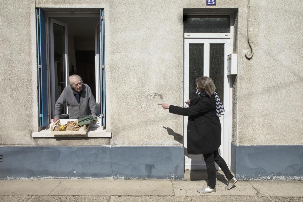 The Graduate Institute and the CEPR co-organize an online public talk by Professor Pierre Yared on his paper "Pandemic Lockdown: The Role of Government Commitment". His work focuses on the importance of credible rules that allow governments to curb a pandemic while limiting the economic costs of a lockdown. This picture shows someone bringing food to an elderly man as part of a neighbourhood solidarity action during the coronavirus lockdown in Fécamp, Normandy, France. Taken by Magnum partner Jean Gaumy.